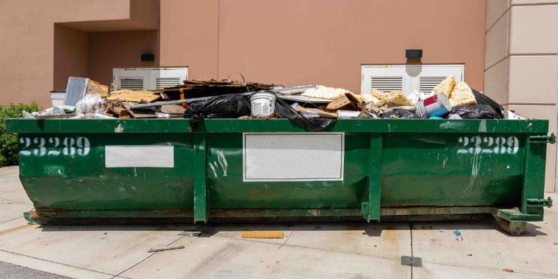 A dumpster with many items on top of it.