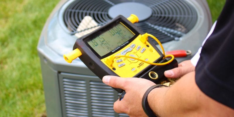 A person holding an electronic device in front of an air conditioner.